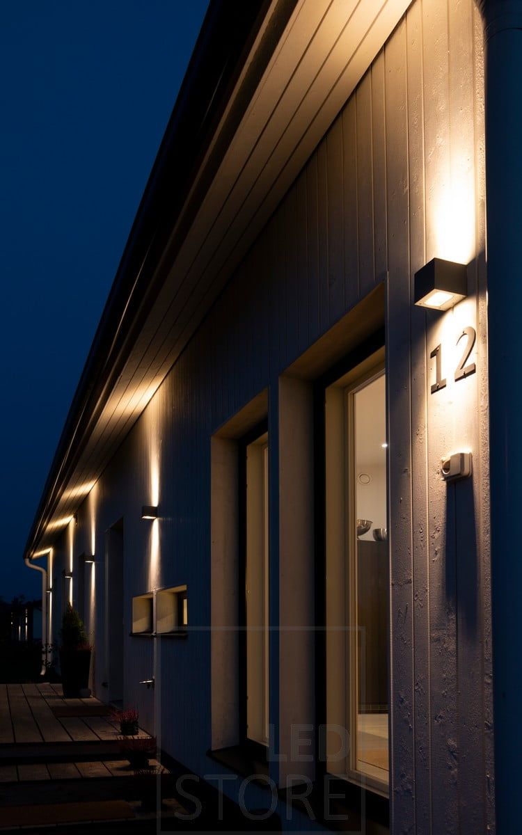 CUBIC OUT led wall light illuminating the facade of a house and the house number.